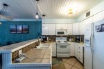 kitchen area, breakfast bar, bar stools, pendant lights, tile counter tops, refrigerator